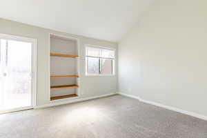 Unfurnished bedroom featuring carpet floors and vaulted ceiling