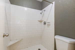 Full bathroom with a textured wall and tiled shower