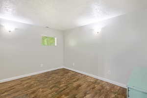 Spare room featuring a textured ceiling and wood finished floors