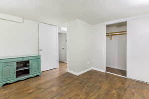 Unfurnished bedroom with a textured ceiling, dark wood finished floors, and a closet