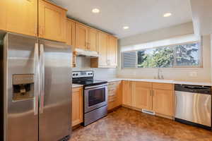 Kitchen with stainless steel appliances, light brown cabinetry, light countertops, and recessed lighting