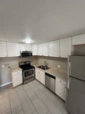 Kitchen with appliances with stainless steel finishes, light countertops, and white cabinets