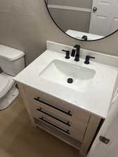 Bathroom with vanity, a textured wall, and wood finished floors