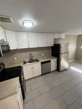 Kitchen featuring appliances with stainless steel finishes, white cabinetry, light countertops, and light tile patterned floors