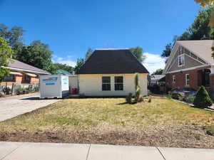 View of front of house with a front yard and roof with shingles