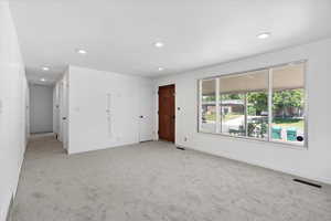 Empty room with light carpet and recessed lighting