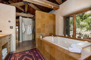 Bathroom featuring a garden tub, a stall shower, vanity, concrete floors, and wooden ceiling