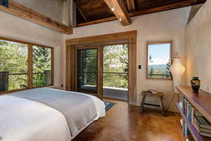 Primary Bedroom with access to outside, finished concrete floors, and wooden ceiling