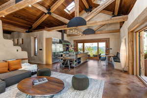 Living area featuring concrete flooring, a wood ceiling with exposed beams, high vaulted ceiling, Velux skylights and stairs