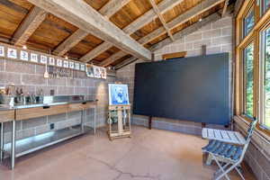 Miscellaneous room with concrete block wall, wood ceiling, and concrete flooring