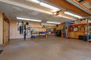 Garage featuring a workshop area, wooden walls, and a garage door opener