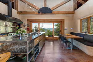 Kitchen featuring  range hood, finished concrete flooring, stainless steel counters, a high ceiling, and a mountain view