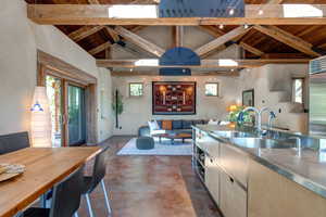 Kitchen featuring stainless steel counters, a wooden ceiling with exposed beams, concrete floors, high end refrigerator, and open floor plan