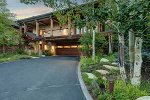 View of front facade with asphalt driveway, a garage, a balcony, and stunning stonework