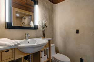 Bathroom featuring a textured wall and wood ceiling