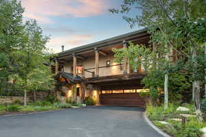 View of front of home featuring a deck/balcony made of IPE wood, a brazilian hardwood, a  driveway, and a built-in garage