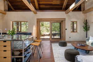 Living area with finished concrete floors and a wood ceiling with exposed beams