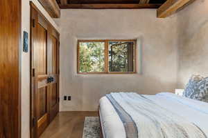 Bedroom with finished concrete flooring and beamed ceiling