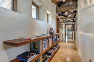 Hall featuring finished concrete flooring, beamed ceiling, high vaulted ceiling