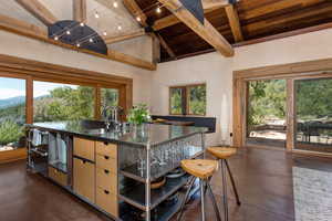Kitchen with finished concrete flooring, beam ceiling, healthy amount of natural light, high vaulted ceiling, and stainless steel counters