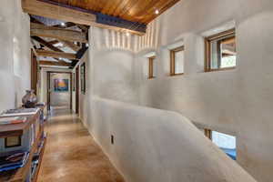 Hall featuring concrete flooring and a wood ceiling with exposed beams