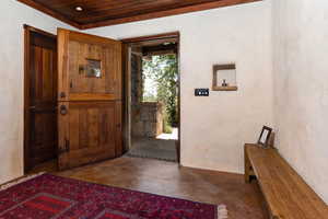 Foyer featuring wood ceiling, a textured wall, and concrete flooring