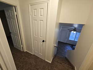 Hallway with dark colored carpet and baseboards