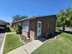 View of side of home featuring brick siding and a lawn