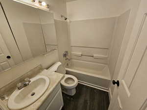 Full bath with shower / bathtub combination, vanity, and dark wood-type flooring
