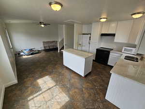 Kitchen with white cabinets, a kitchen island, white appliances, light stone countertops, and a textured ceiling
