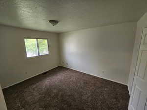 Unfurnished room featuring dark carpet and a textured ceiling