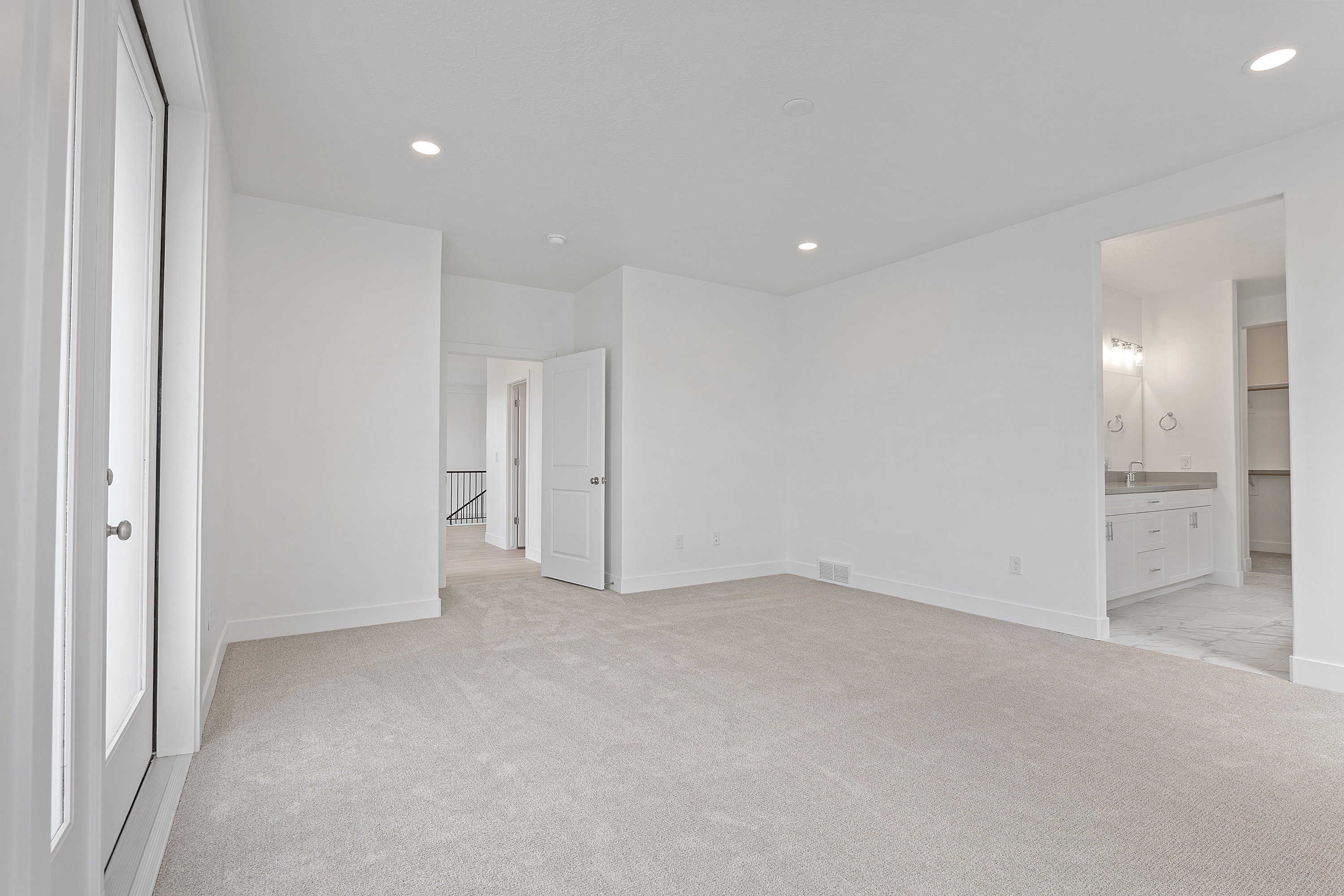 Unfurnished bedroom with light colored carpet, recessed lighting, and ensuite bath