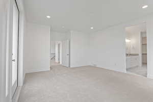Unfurnished bedroom with light colored carpet, recessed lighting, and ensuite bath
