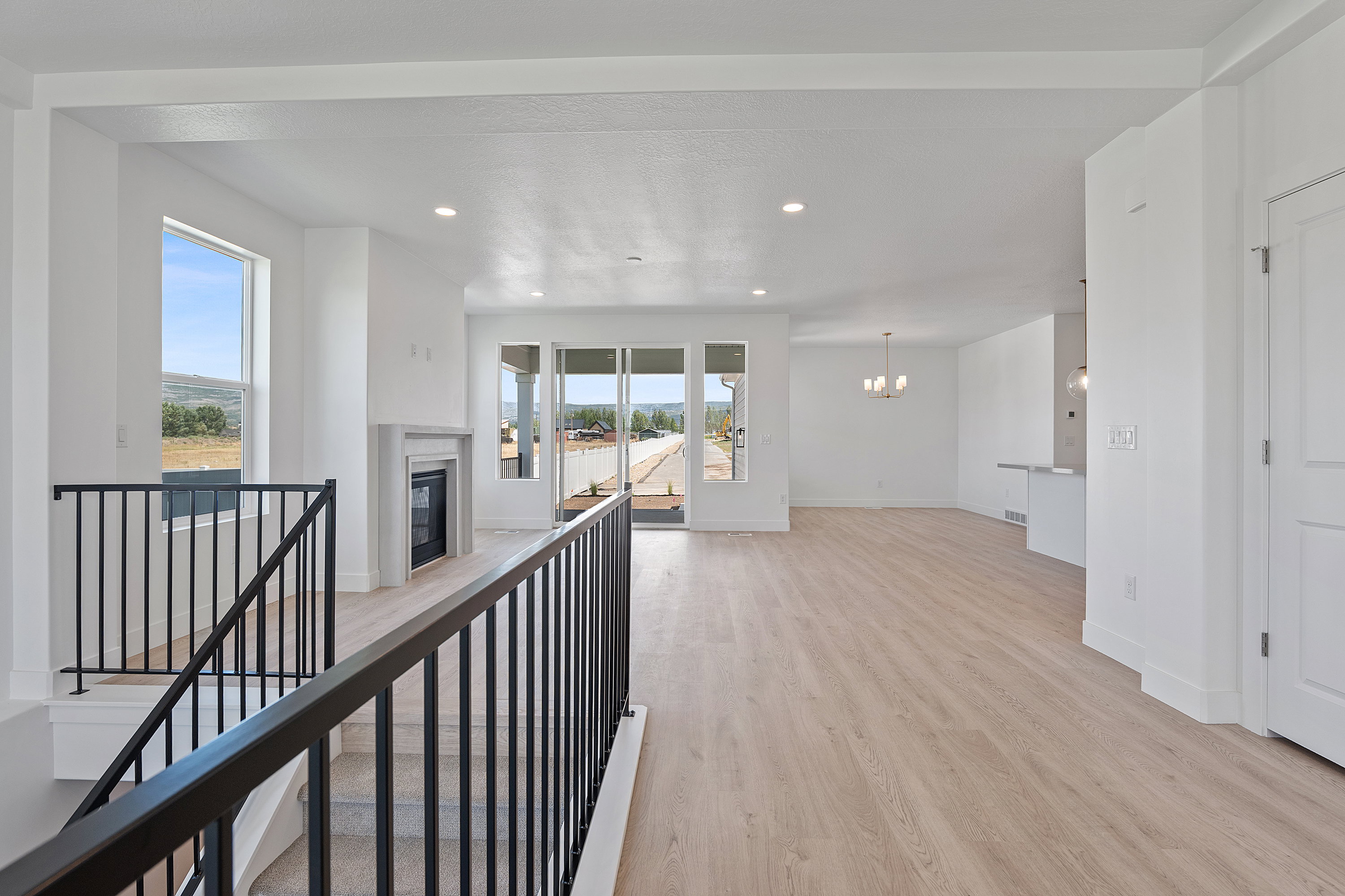 Hallway with light wood-style floors, a chandelier, recessed lighting, and an upstairs landing