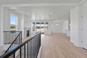 Hallway with light wood-style floors, a chandelier, recessed lighting, and an upstairs landing
