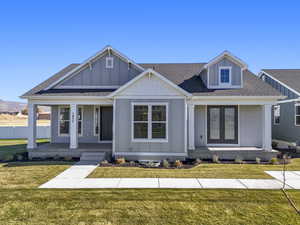 View of front of property featuring roof with shingles, a front lawn, board and batten siding, and a porch