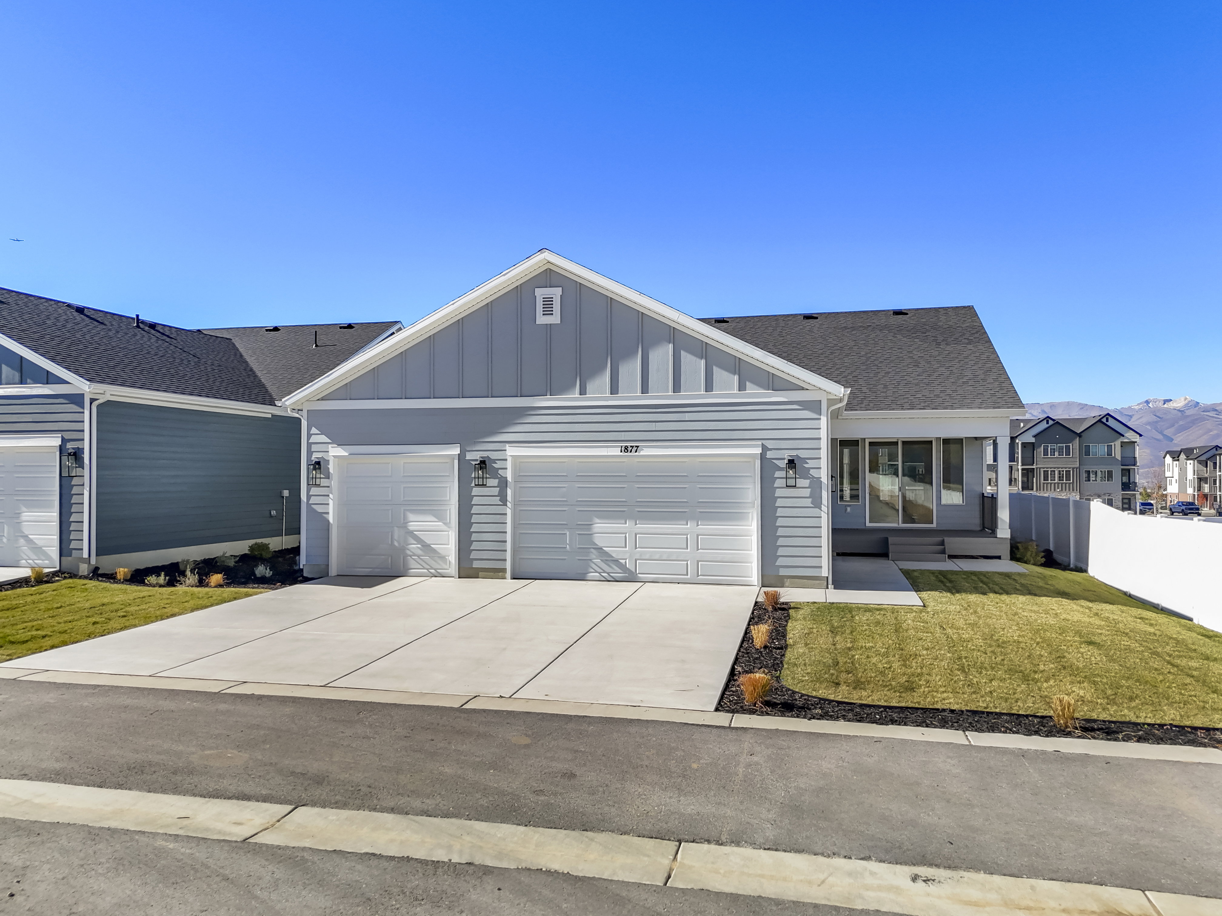 Ranch-style house with board and batten siding, concrete driveway, an attached garage, and roof with shingles