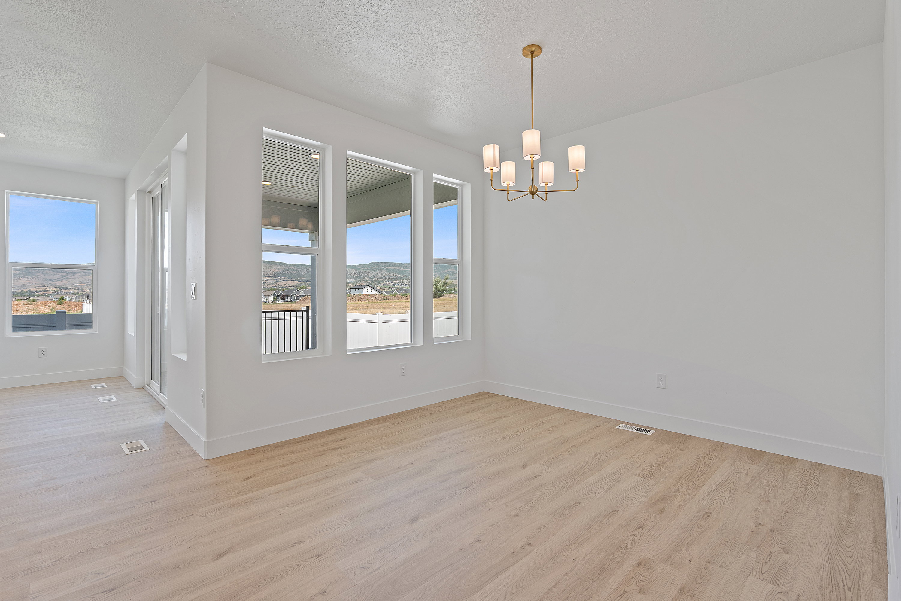 Unfurnished dining area featuring plenty of natural light, light wood-type flooring, a chandelier, and a textured ceiling