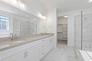 Full bathroom with a marble finish shower, marble look tiles, double vanity, recessed lighting, and a spacious closet