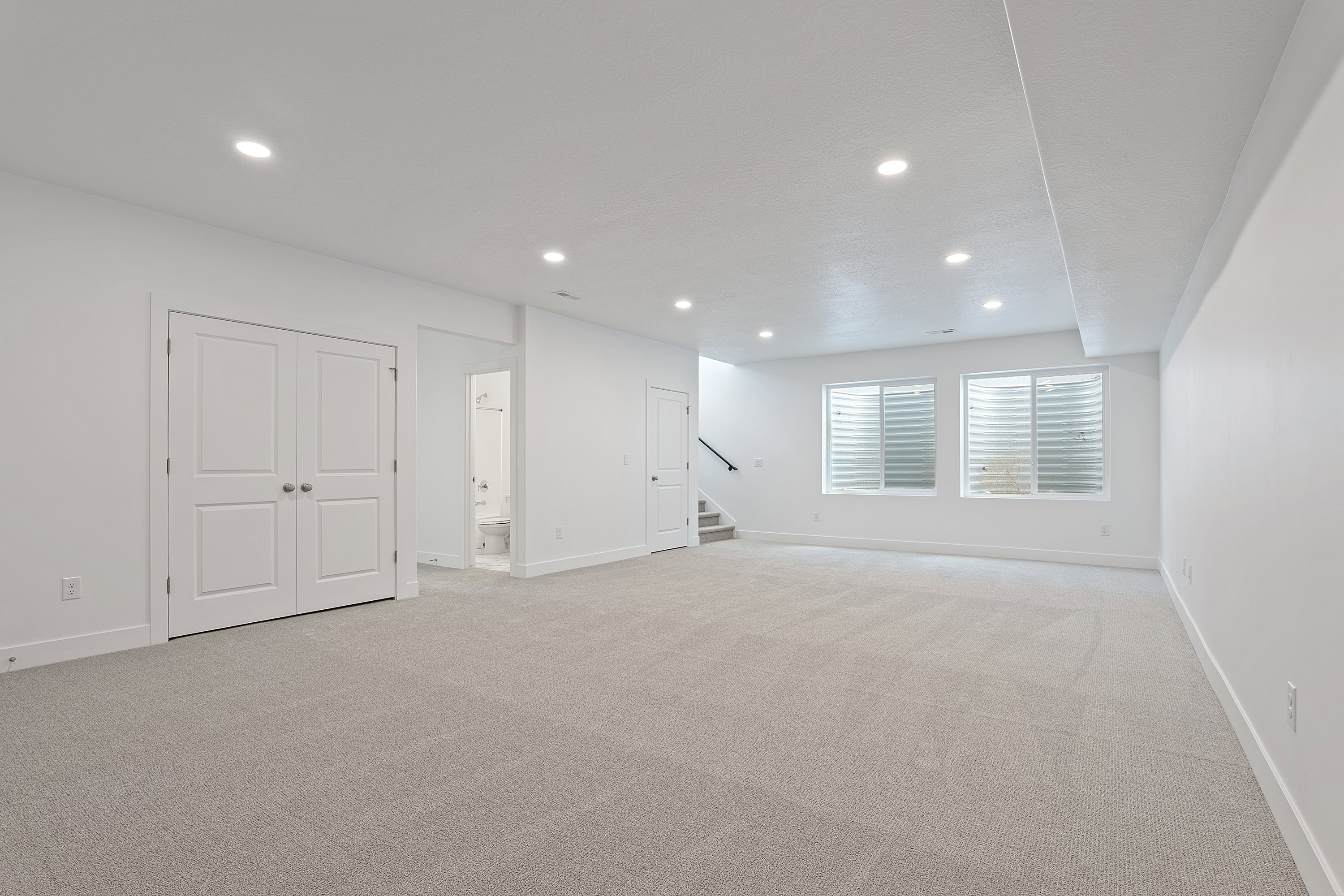 Below grade area featuring light carpet, recessed lighting, and stairs