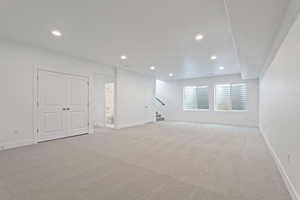 Below grade area featuring light carpet, recessed lighting, and stairs