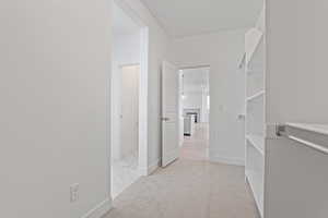 Corridor featuring baseboards and light colored carpet