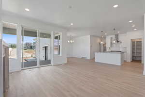 Unfurnished living room with light wood-type flooring, a chandelier, and recessed lighting