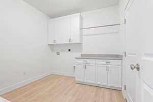 Laundry room featuring hookup for an electric dryer, cabinet space, light wood-style floors, and hookup for a washing machine
