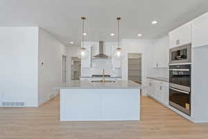 Kitchen featuring backsplash, stainless steel double oven, light countertops, white cabinets, and recessed lighting