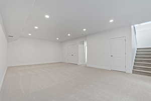 Below grade area featuring light carpet, stairway, and recessed lighting