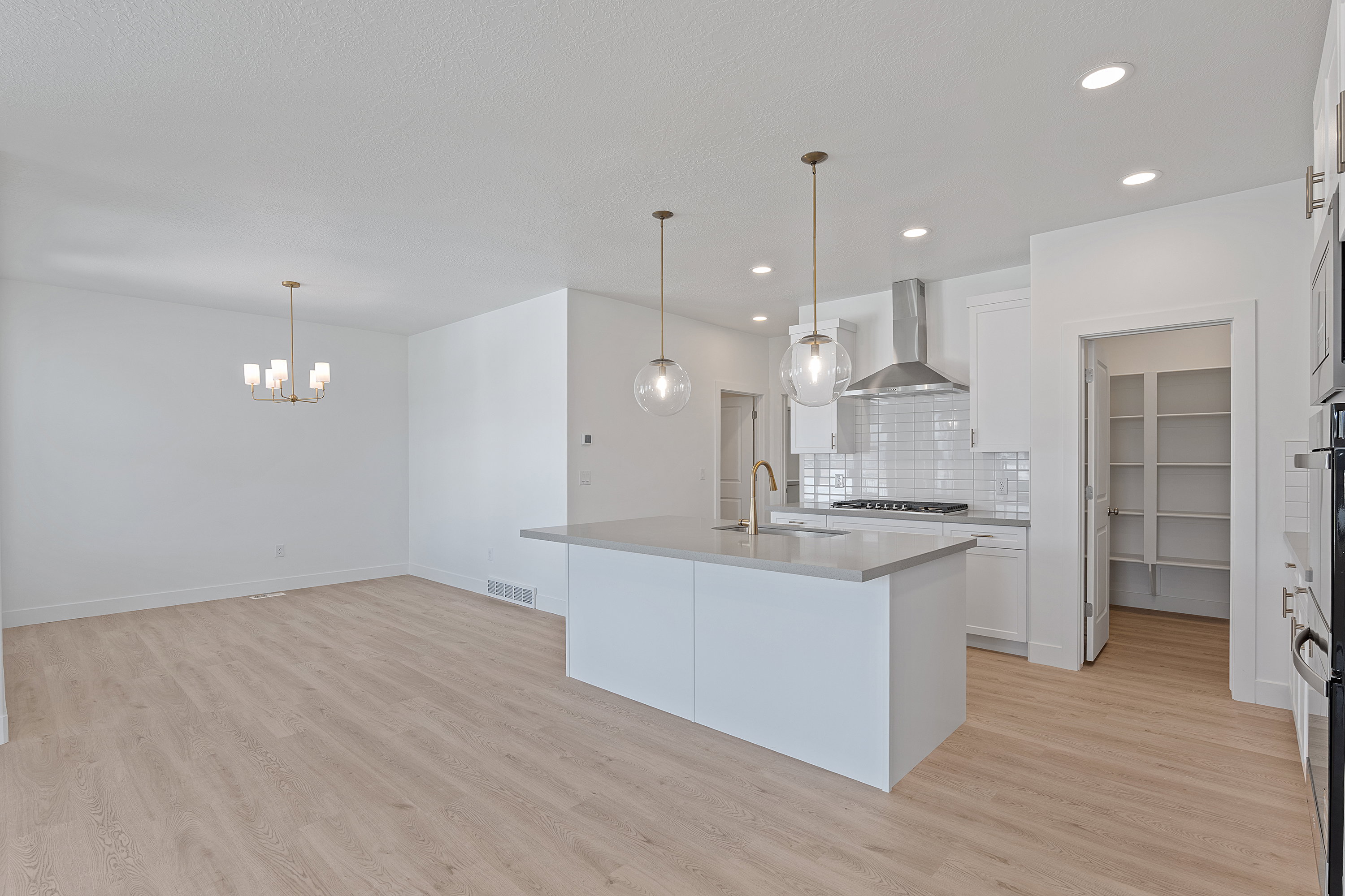 Kitchen with backsplash, white cabinets, light wood finished floors, wall chimney exhaust hood, and light countertops