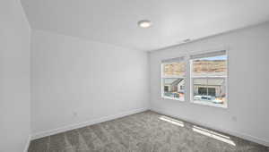 Carpeted spare room featuring baseboards