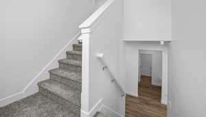 Stairway with wood finished floors and a towering ceiling