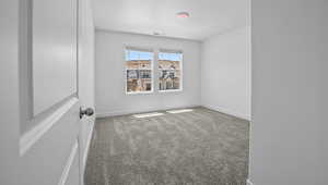Carpeted empty room featuring baseboards